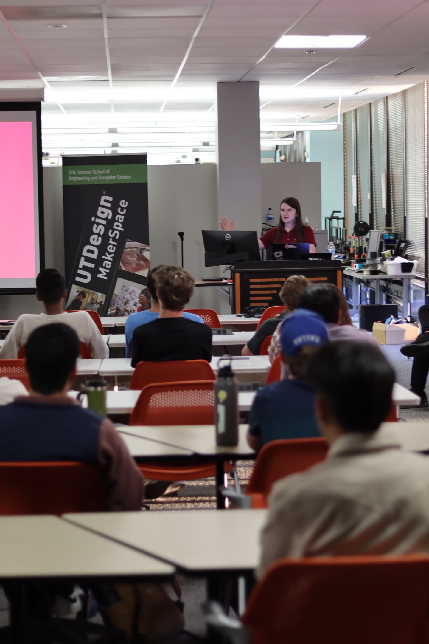 Natalie presenting to a group of college students wearing a red polo